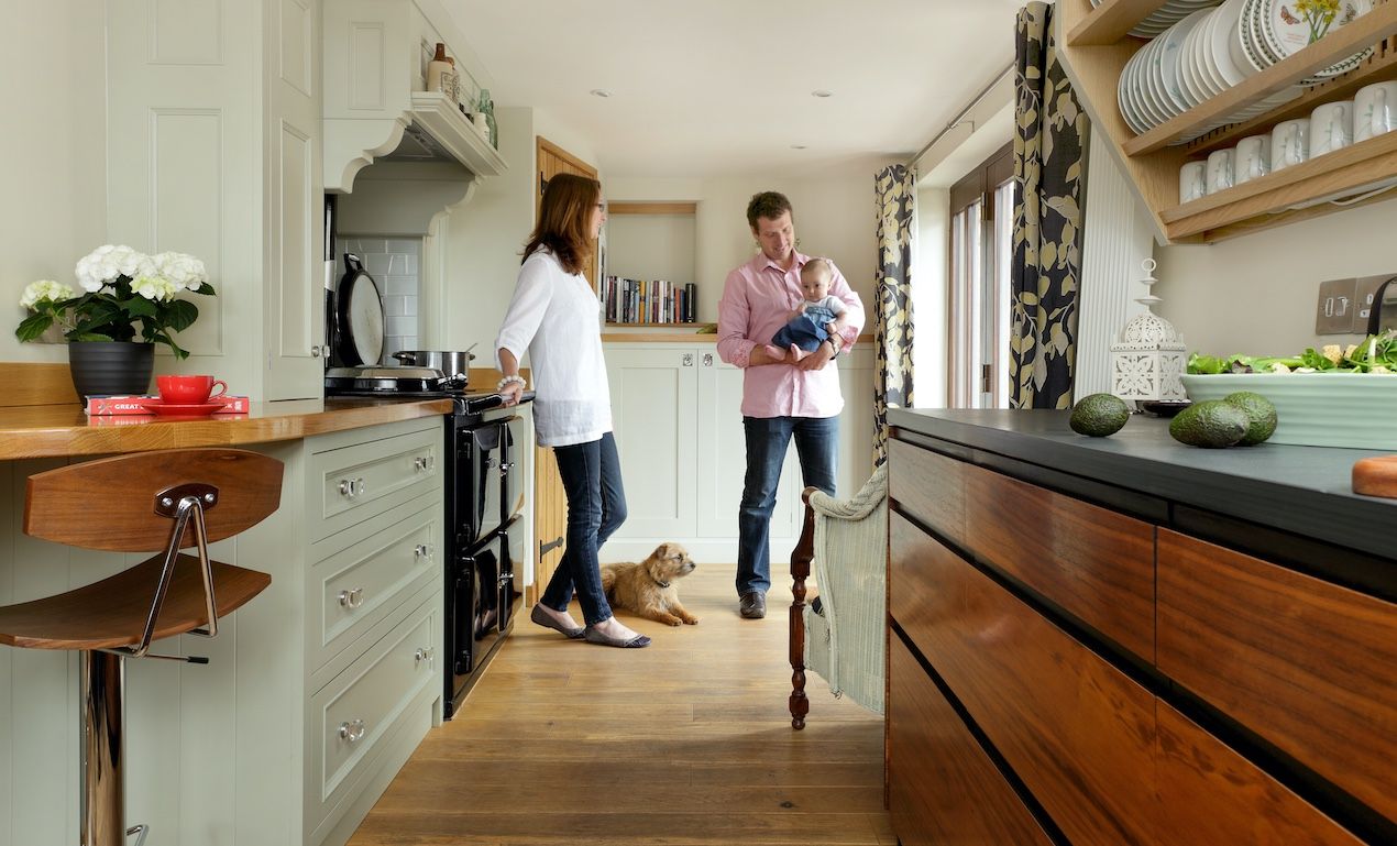 couple standing in kitchen with baby and dog