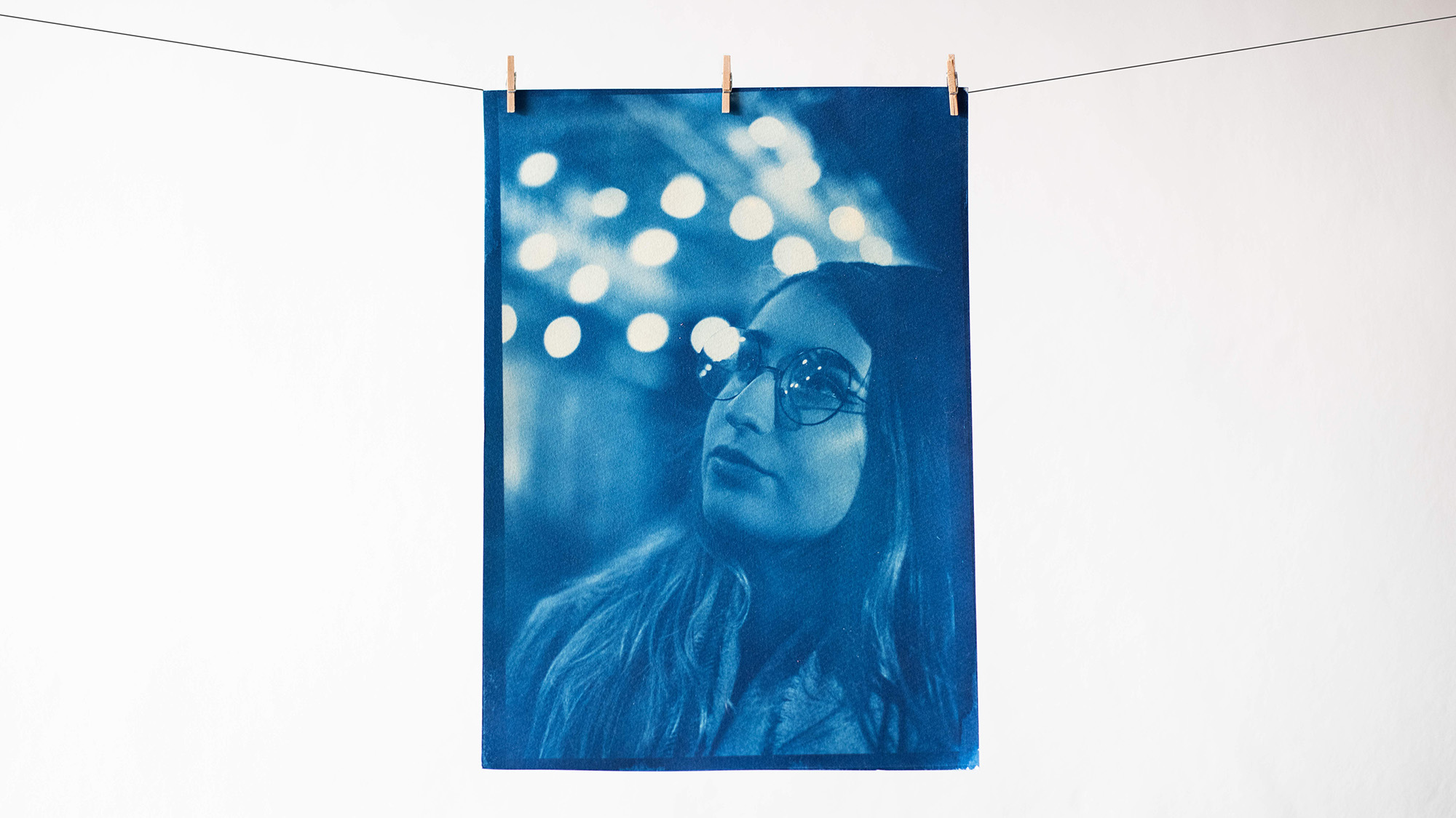 Finished cyanotype print hung on a piece of string to dry