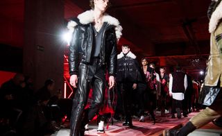 A group of male models on the cat walk modelling Alexander McQueen clothing