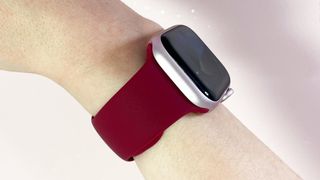 A red silicone Apple Watch-compatible strap is worn on a woman's wrist, with the watch face turned slightly away from the camera.