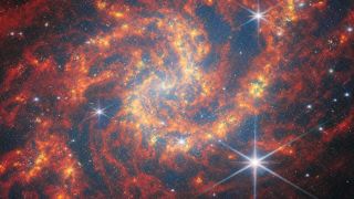 A red and orange spiral galaxy image with lots of stars.