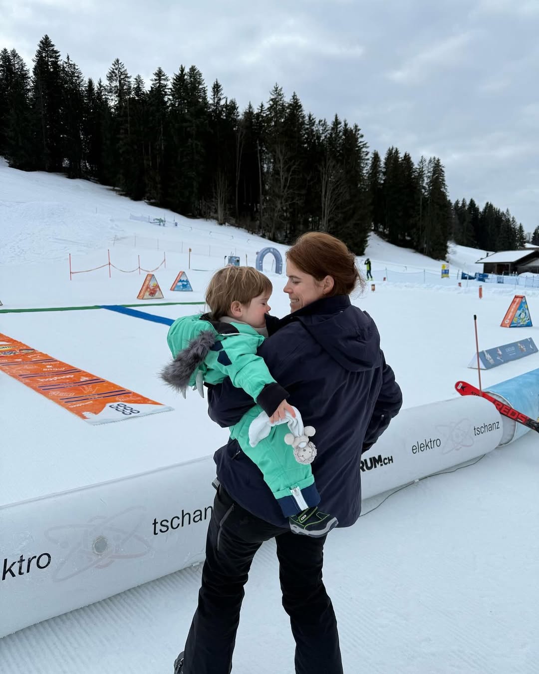 Princess Eugenie wearing a coat standing in snow with her son Ernest