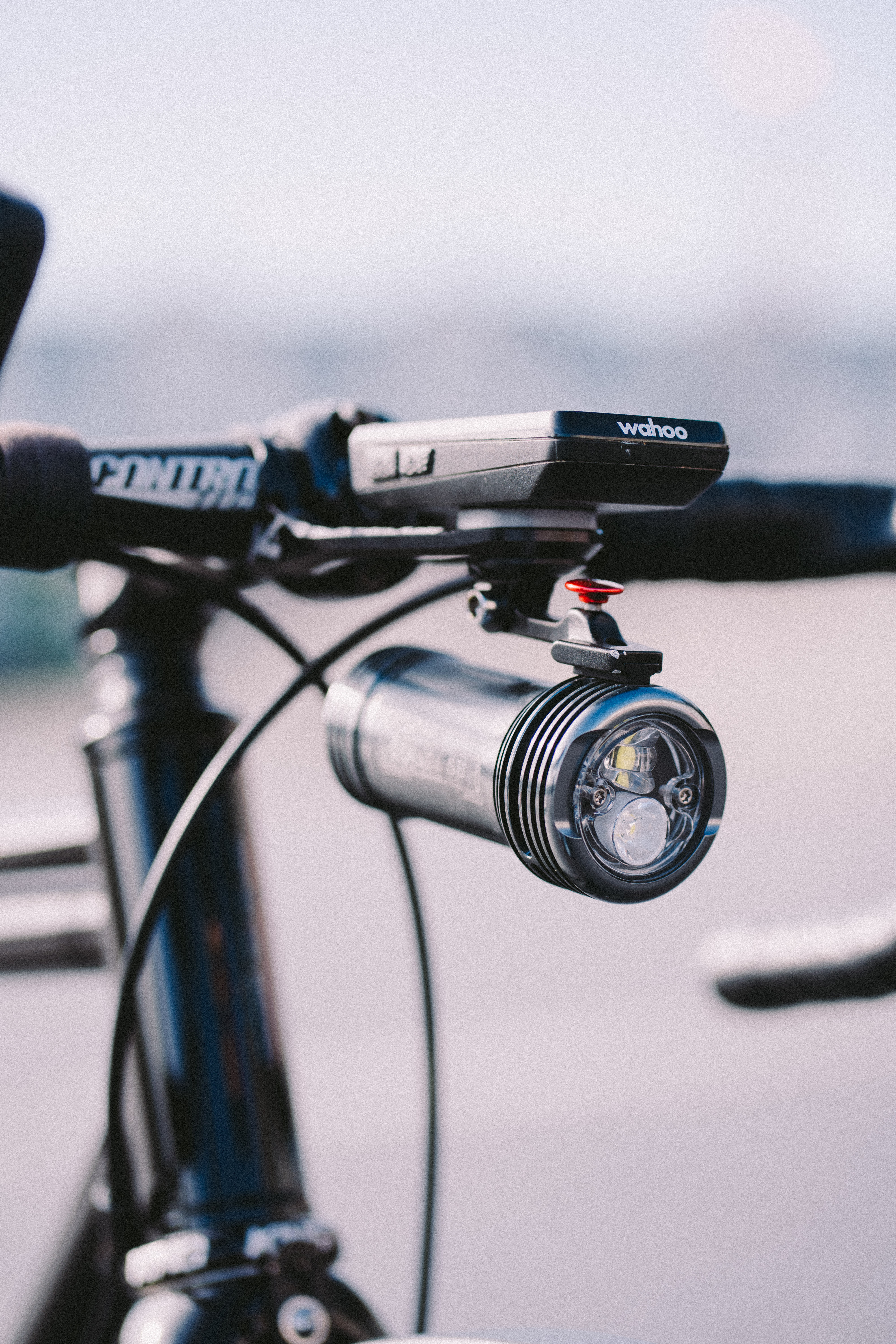 A large silver bike light slung beneath a bike computer