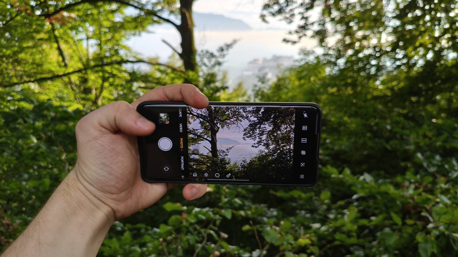The Realme 15 Pro Game of Thrones Edition ahead of a leafy background and a distant fortress.