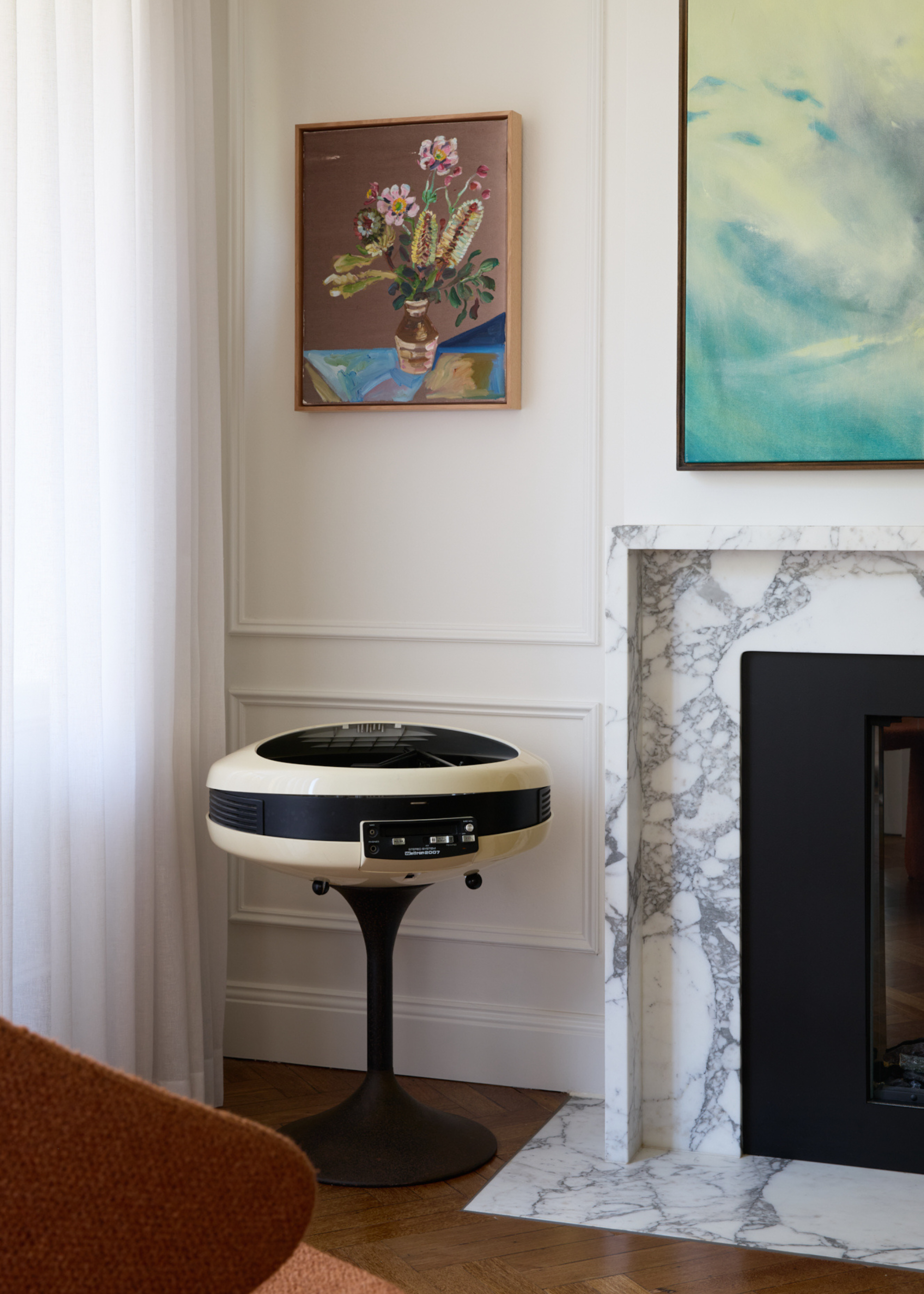 A living room with a speaker, a atone fireplace and framed art