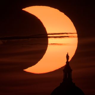 A partial solar eclipse is seen as the sun rises behind the Statue of Freedom atop the United States Capitol Building on June 10, 2021, as seen from Arlington, Virginia by NASA photographer Bill Ingalls..
