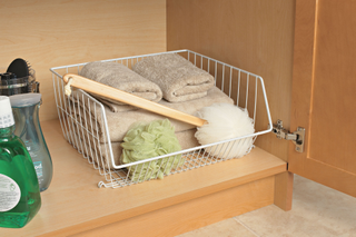 bathroom under the sink storage, white basket with towels, cleaning products