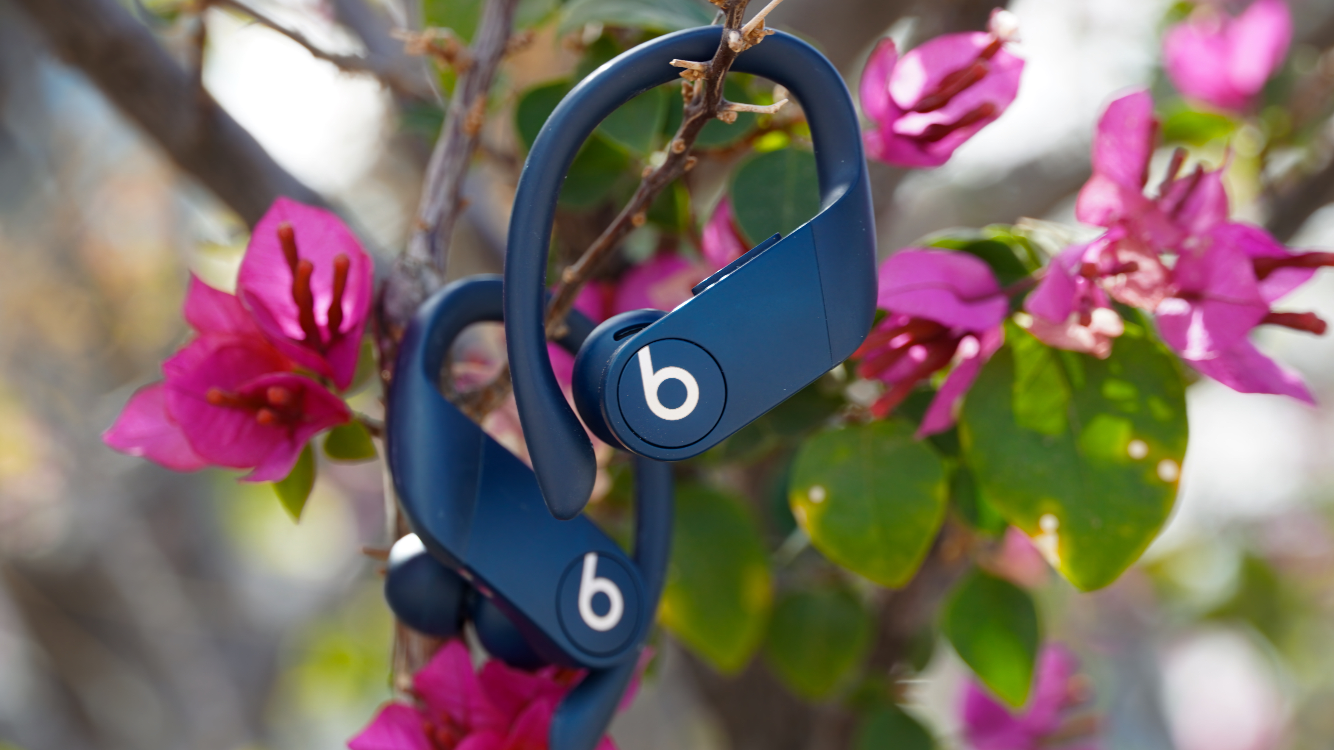 The orange Powerbeats Pro 2 next to the Navy original Powerbeats Pro.