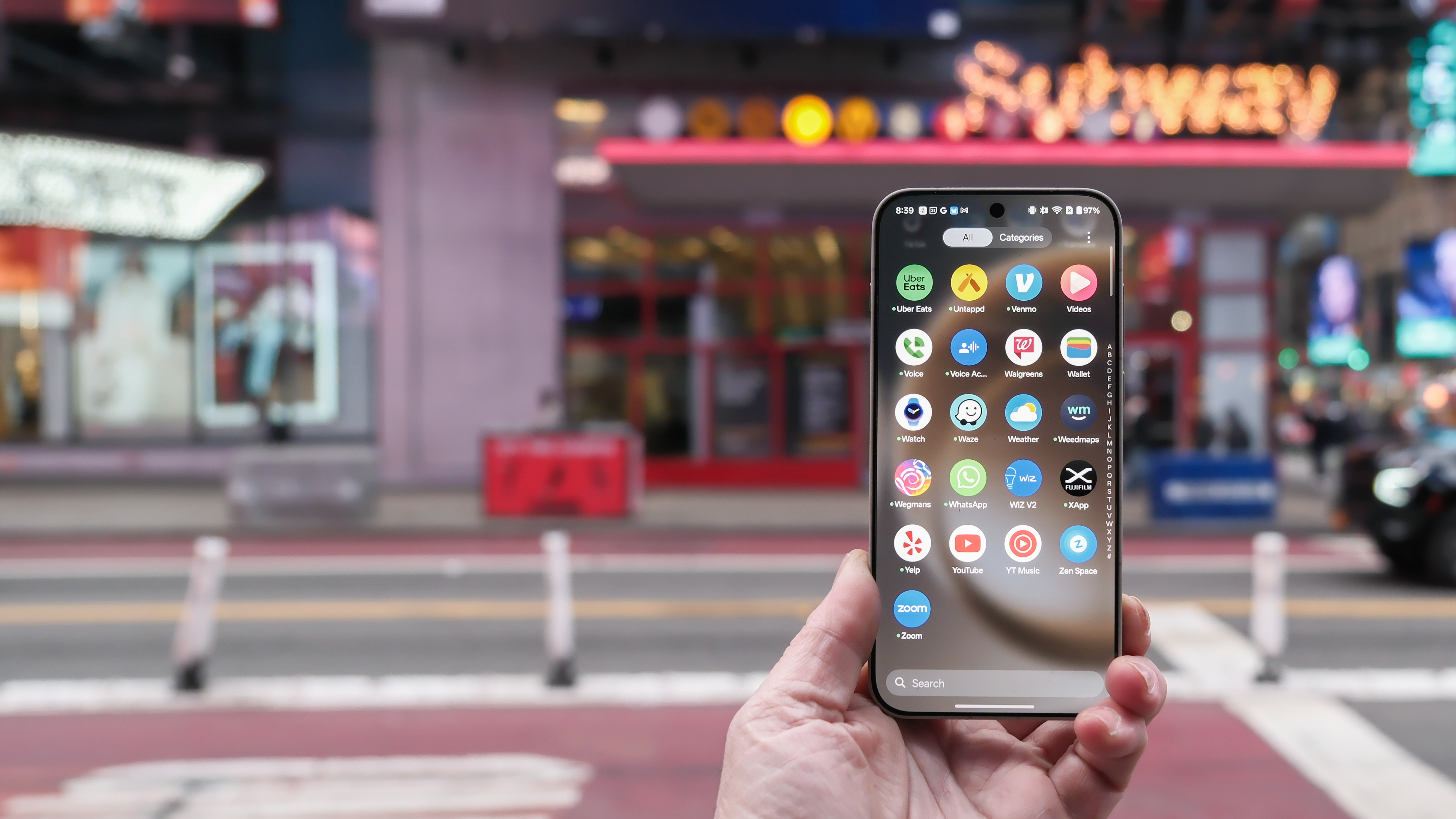 OnePlus 15 in Times Square New York City on the busy street showing the cameras and sides of the phone in addition to home screen panels and Settings menus