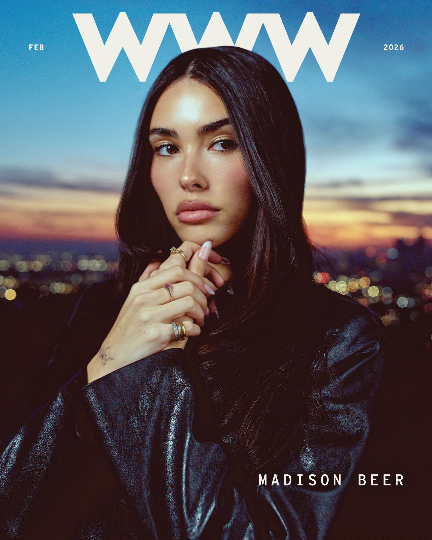 Cover image from Who What Wear's February cover story with Madison Beer. The image features the Who What Wear logo with &amp;quot;February 2026&amp;quot; and Beer's name written on it. The Los Angeles skyline at sunset is in the background as Beer holds her hands up to her chin and looks off camera. She is wearing a black leather coat and layered rings.