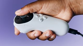 A single hand hold the Xbox Adaptive Joystick with a purple background.