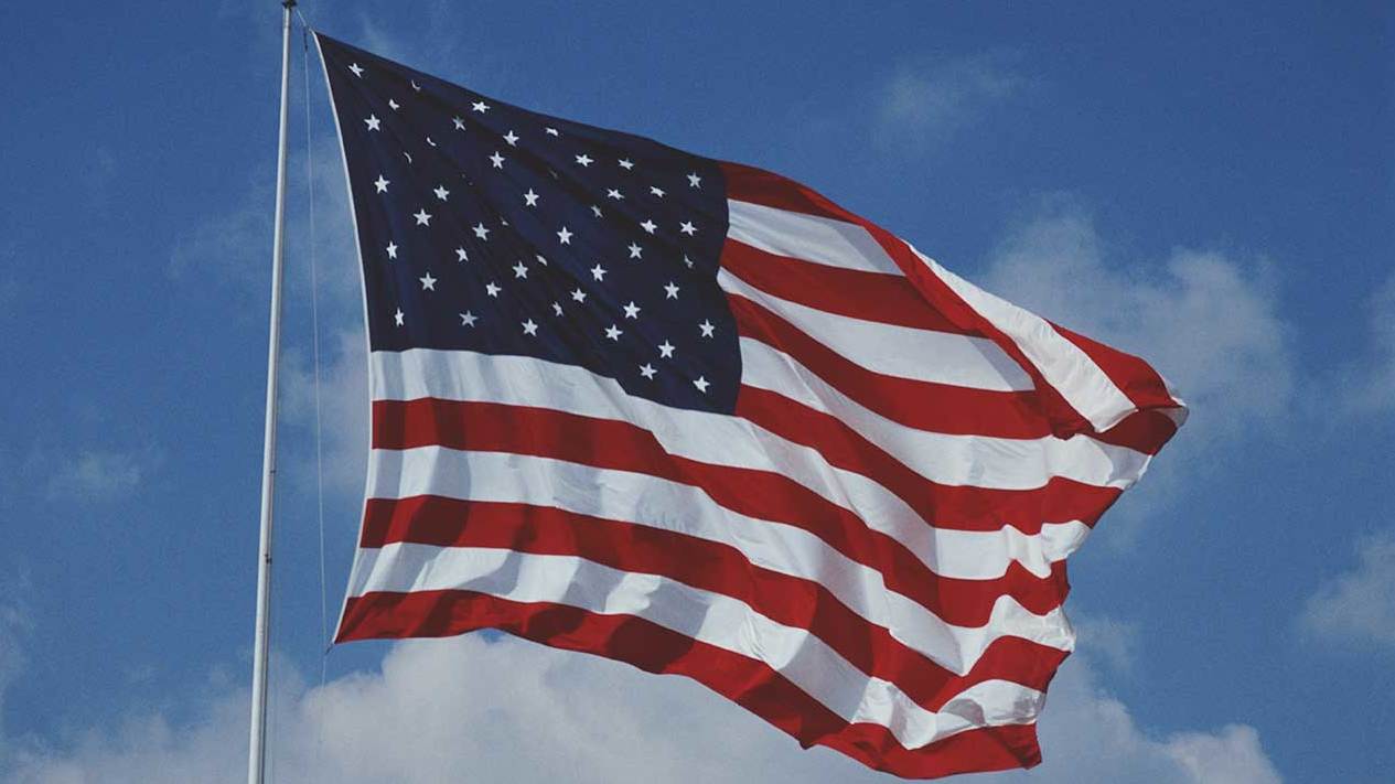 The United States flag flying in a blue sky