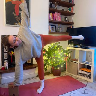 Woman wearing red leggings, white socks and grey sweater practicing yoga