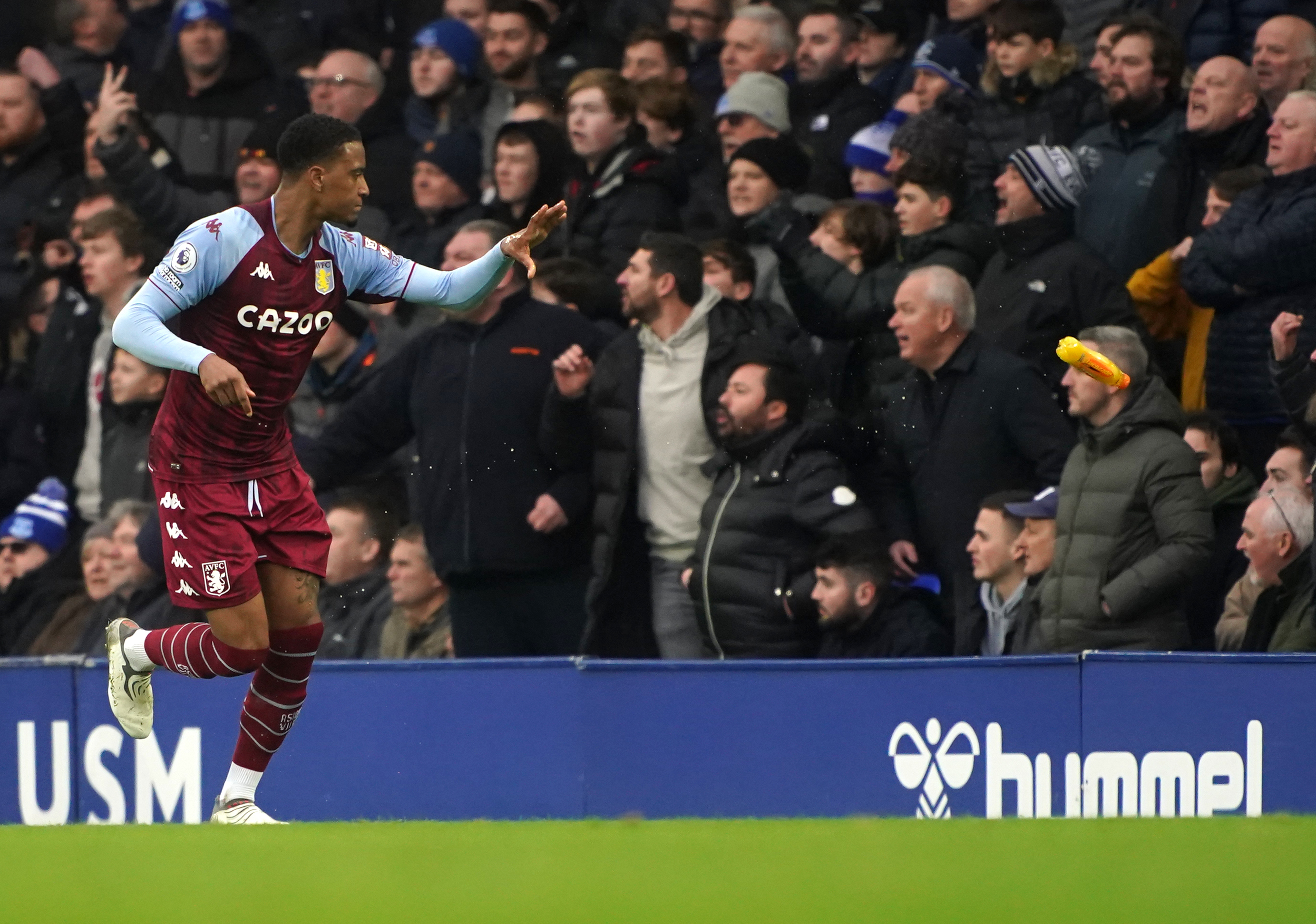 Aston Villa's Ezri Konsa tosses a bottle to the touchline after it was thrown onto the pitch