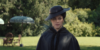 Almila Bagriacik as Leontine von Apafi wearing a black cloak and hat walking through a lawn in 'The Empress.'