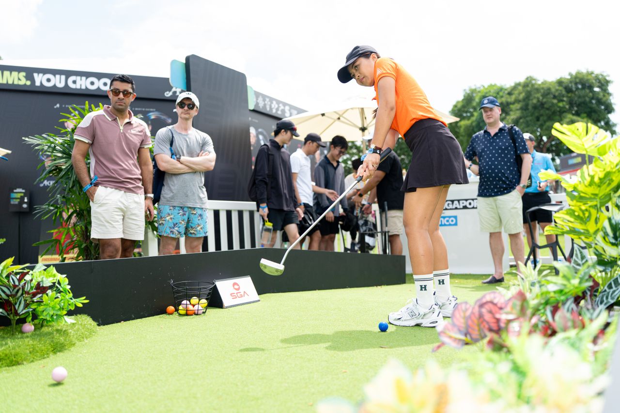 A golfer hits a putt at a LIV Golf fan village