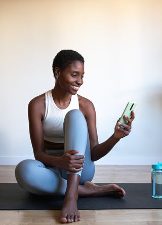 Woman practising yoga and looking at a phone