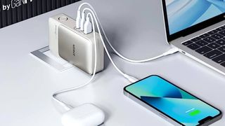 Anker 733 power bank on white desk connected to laptop and smartphone