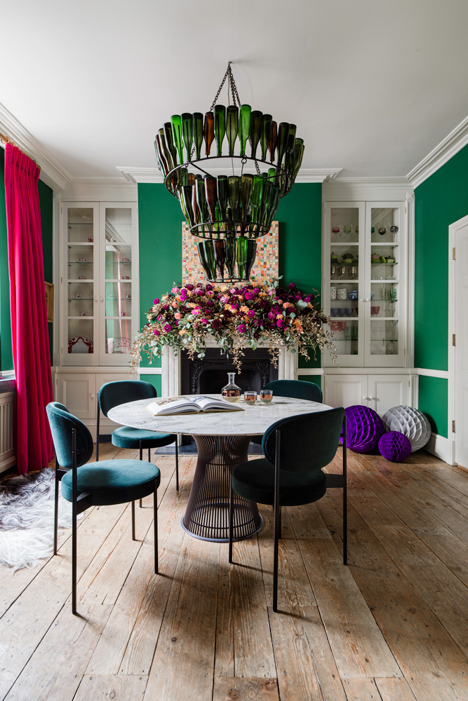 Green dining room with bright pink curtain and statement green bottle chandelier