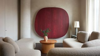 living room with limewash paint on walls, boucle sofas, and red timber cabinet concealing the tv