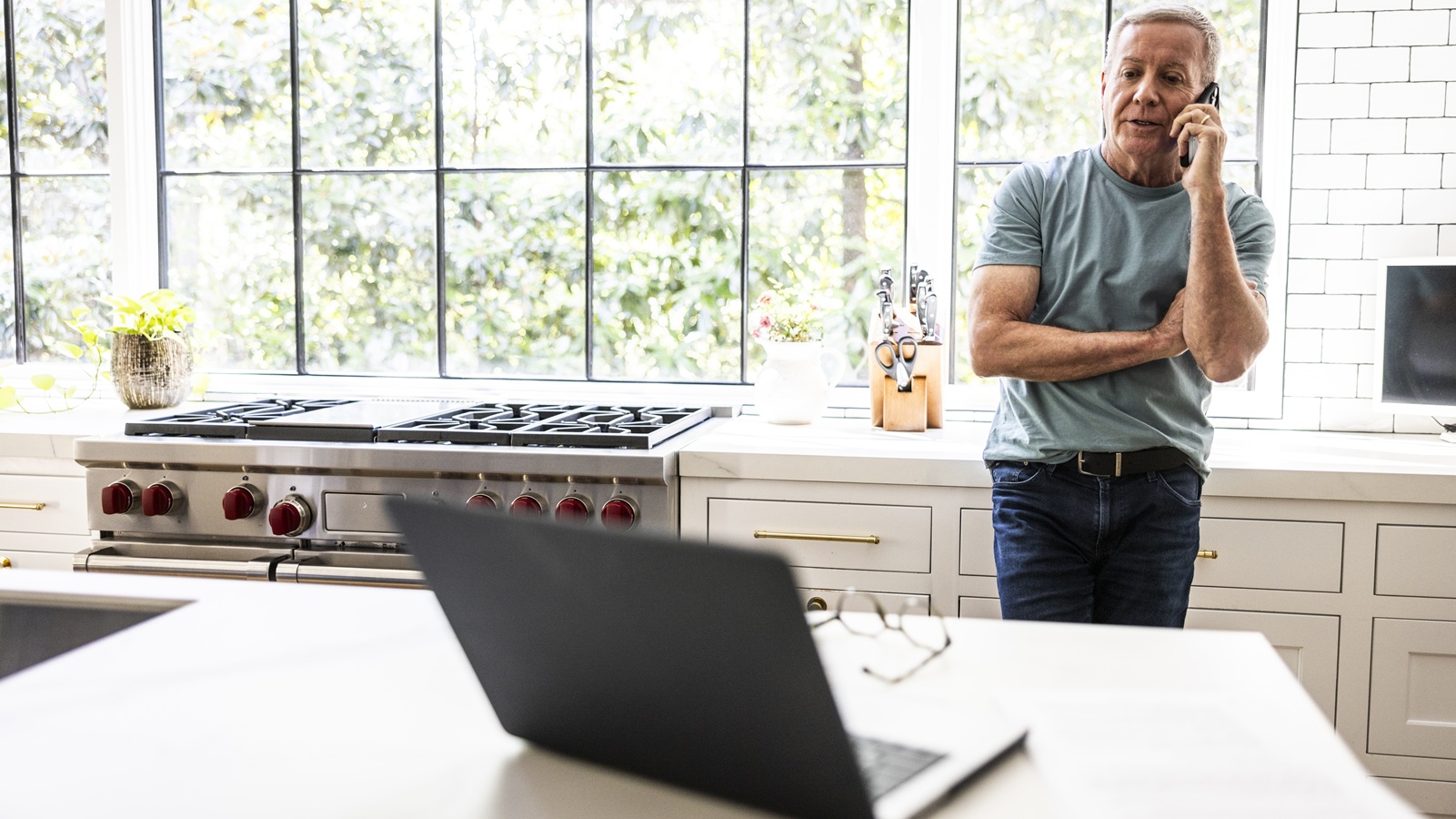 Senior man talking on smartphone in kitchen