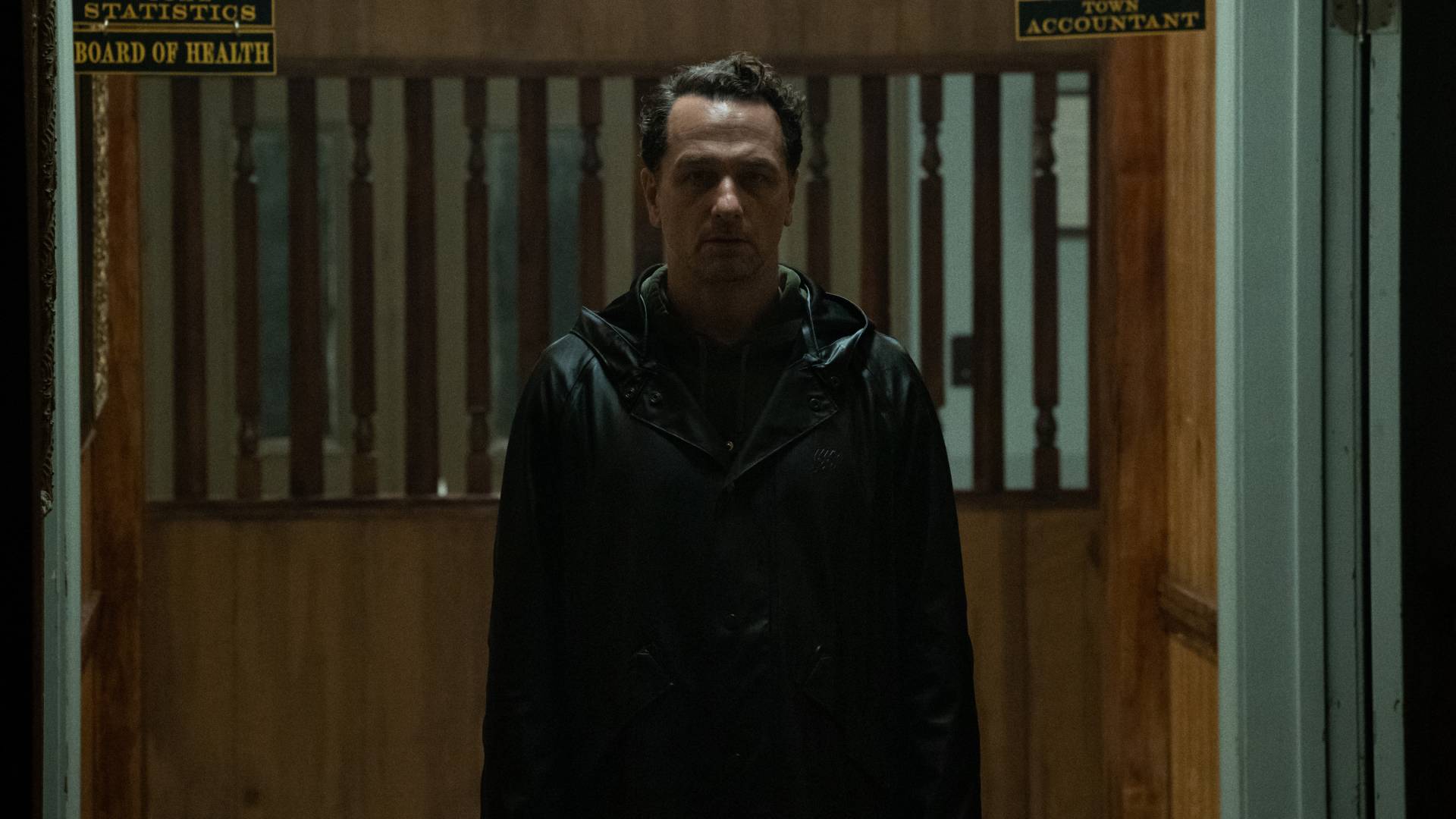 Matthew Rhys as Tom Loflis wearing a raincoat in Widow's Bay