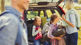 Camping with kids: a family unload camping gear from the boot of their car