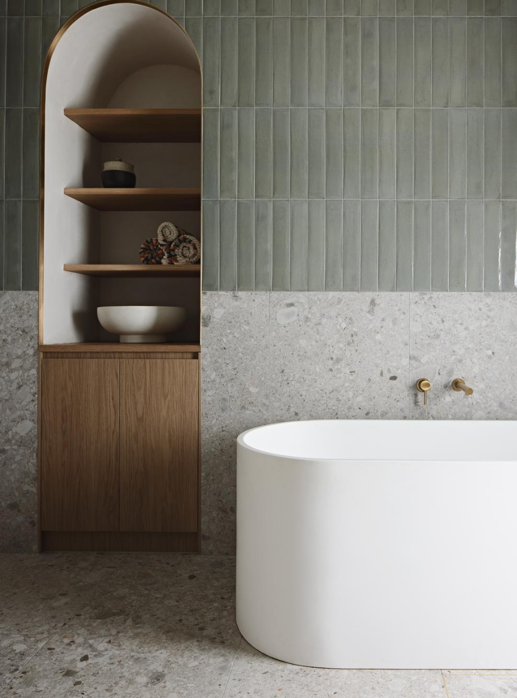 Sage green bathroom with terrazzo tiles and arched open shelving