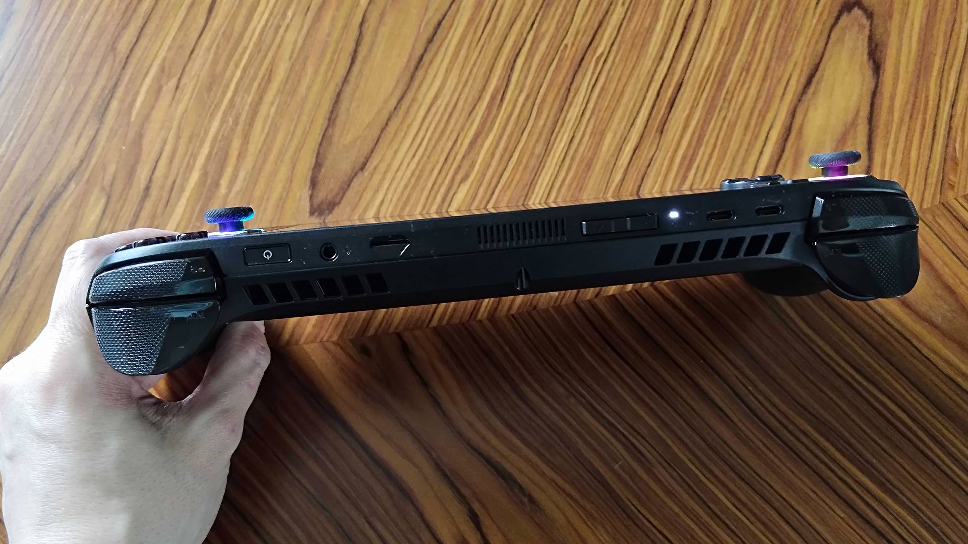 Top view of ROG Xbox Ally X top USB-C ports and triggers on woodgrain table.