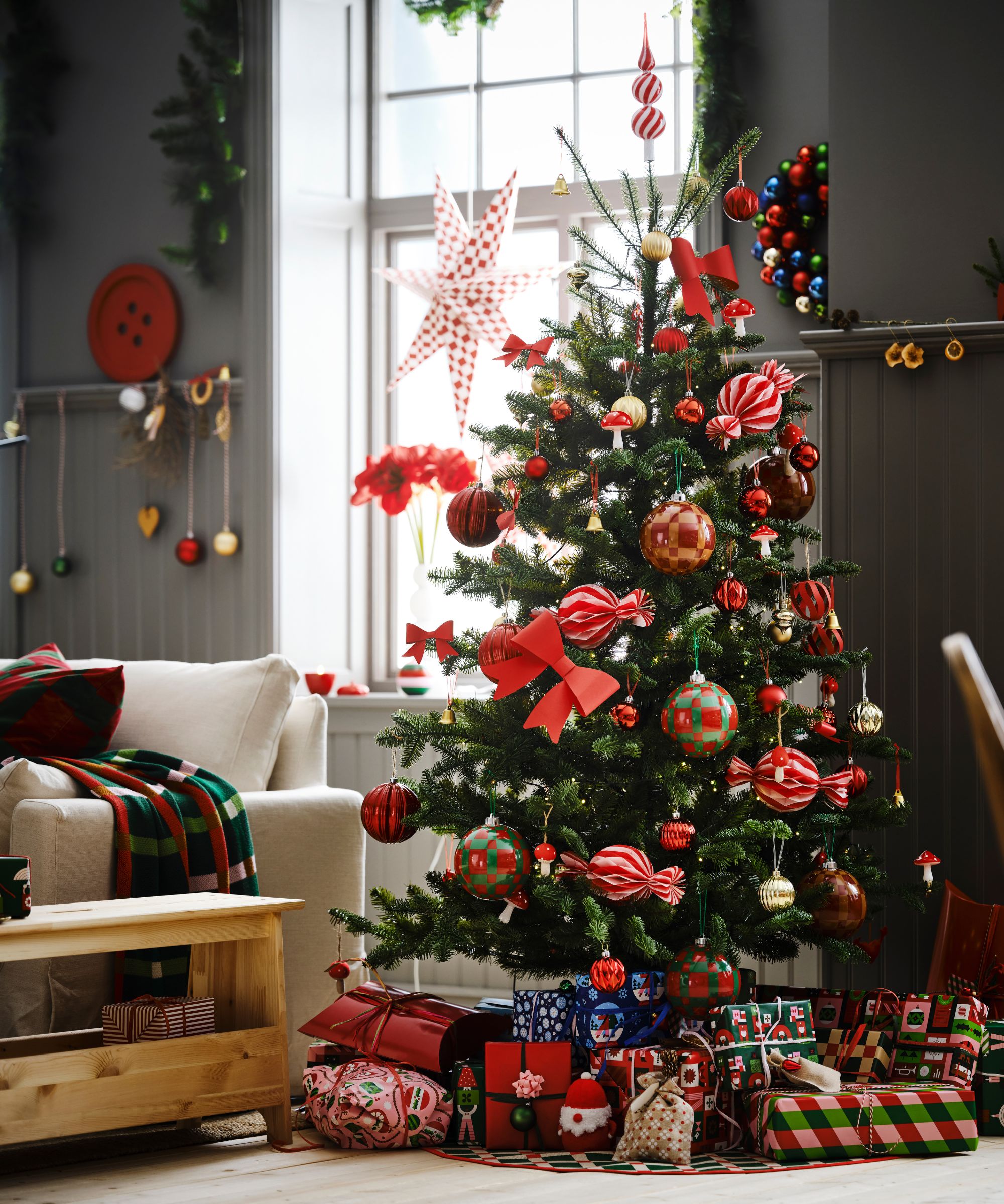 gray panelled living room with a white couch, wooden side table all decorated for christmas with a large christmas tree decorated with color and kitsch ornaments