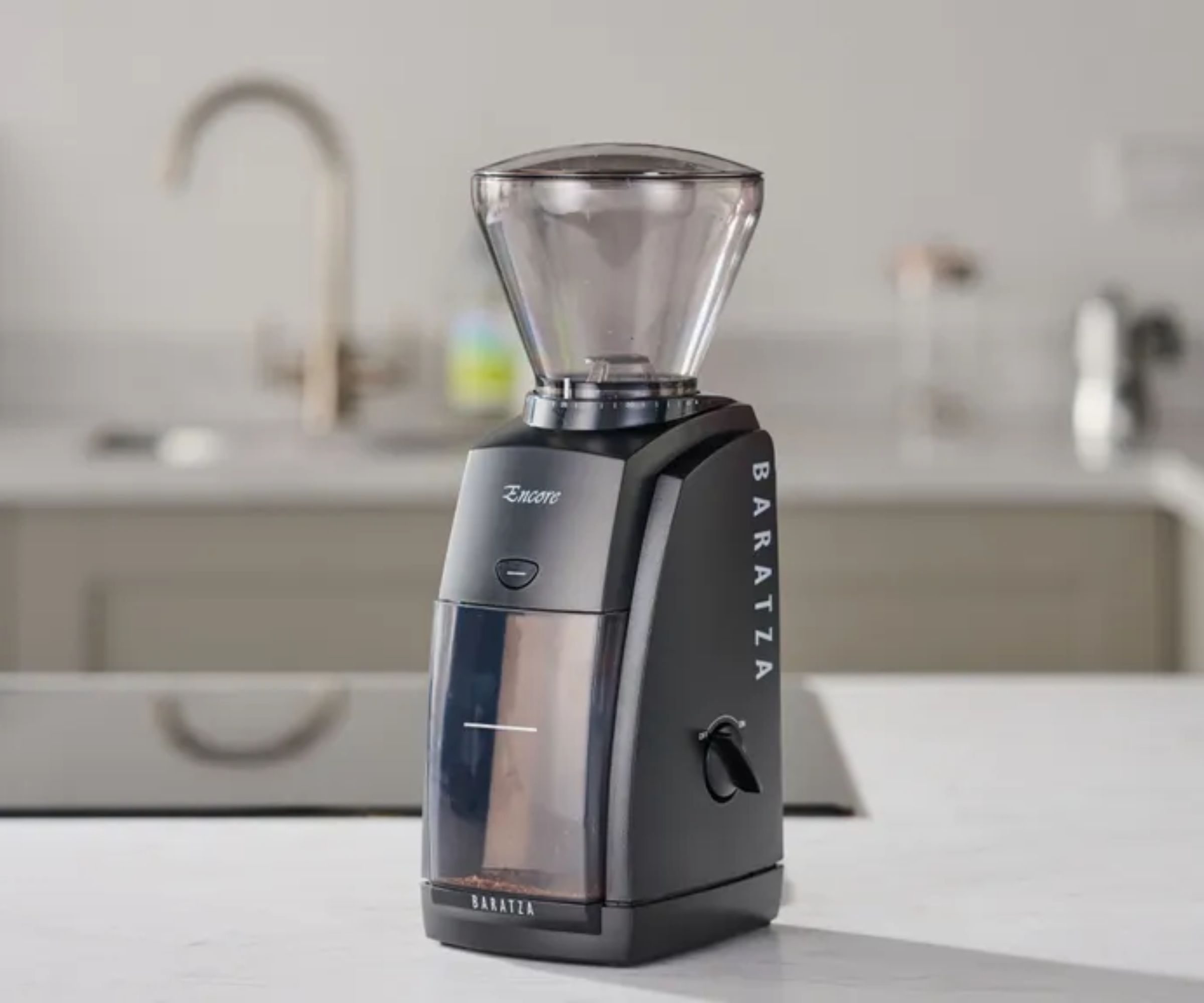 A compact grey plastic coffee grinder with a clear hopper on top. 
