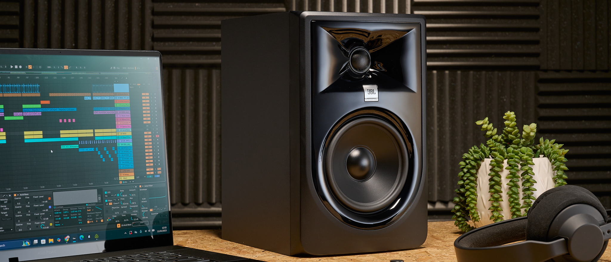A JBL 305P MKII studio monitor on a studio desk with laptop and headphones