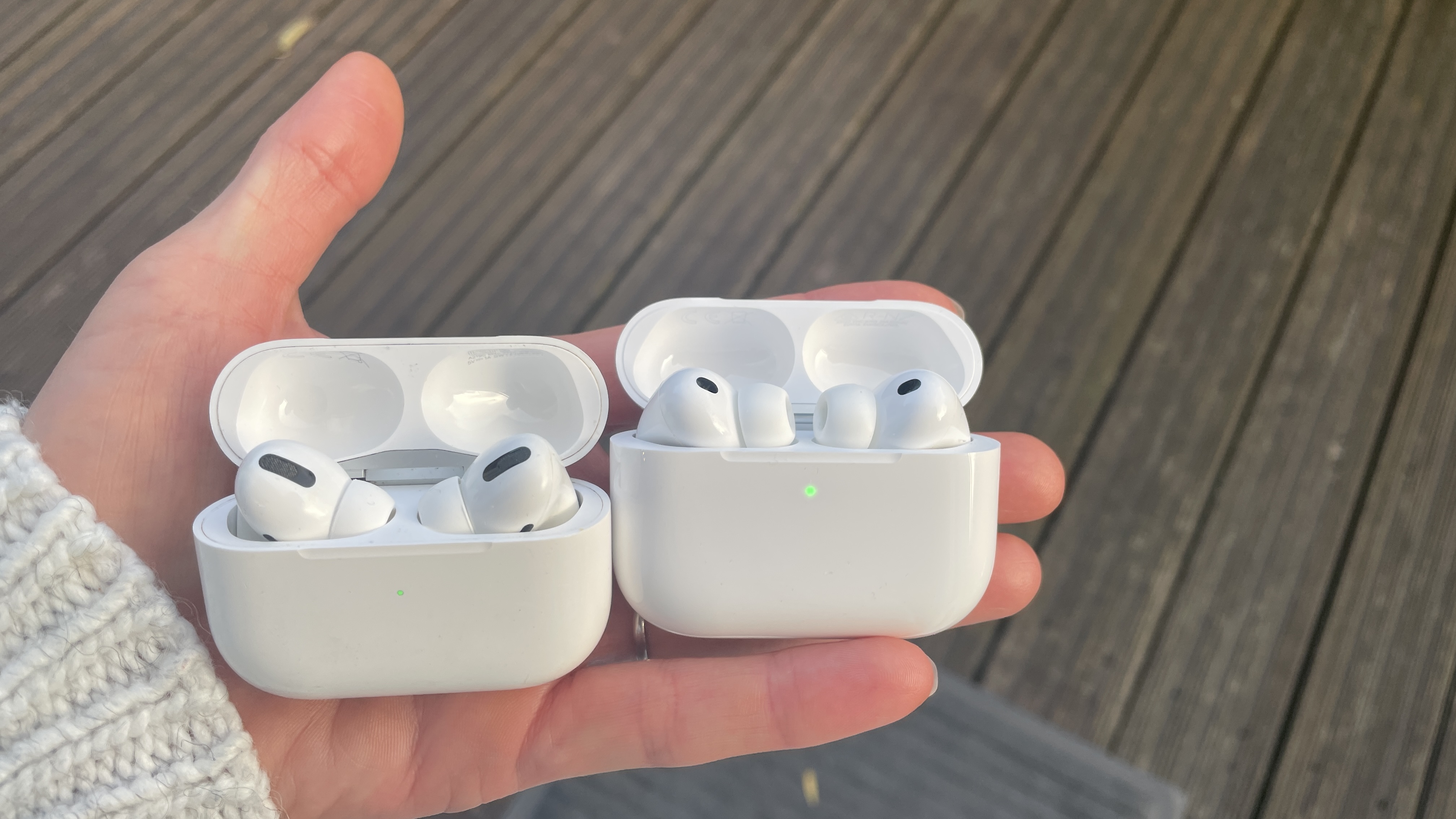 Apple AirPods Pro 3 held in a hand, with beige woollen background