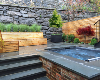 Wooden L-shaped storage bench in back yard with rain