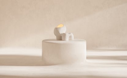 Two pale light sculptures on a stone plinth against pale background