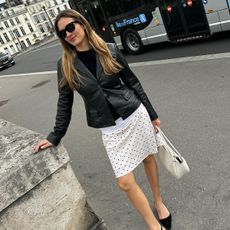 French influencer wearing a black leather blazer and white polka dot skirt