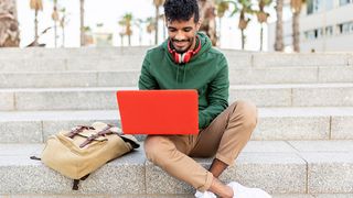 A student using one of the best student laptops while sitting outside on steps