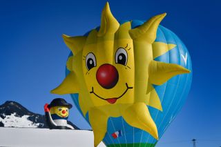 A blue hot air balloon with a yellow sun on it at Chateau-d'Oex