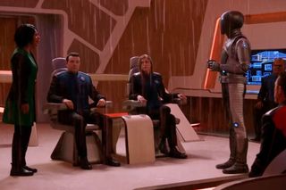 I'm just an AI from Kaylon-1, standing in front of a ship's doctor, asking her to forgive him. Isaac (Mark Jackson) apologizes for his behavior to Dr. Finn (Penny Johnson Jerald).