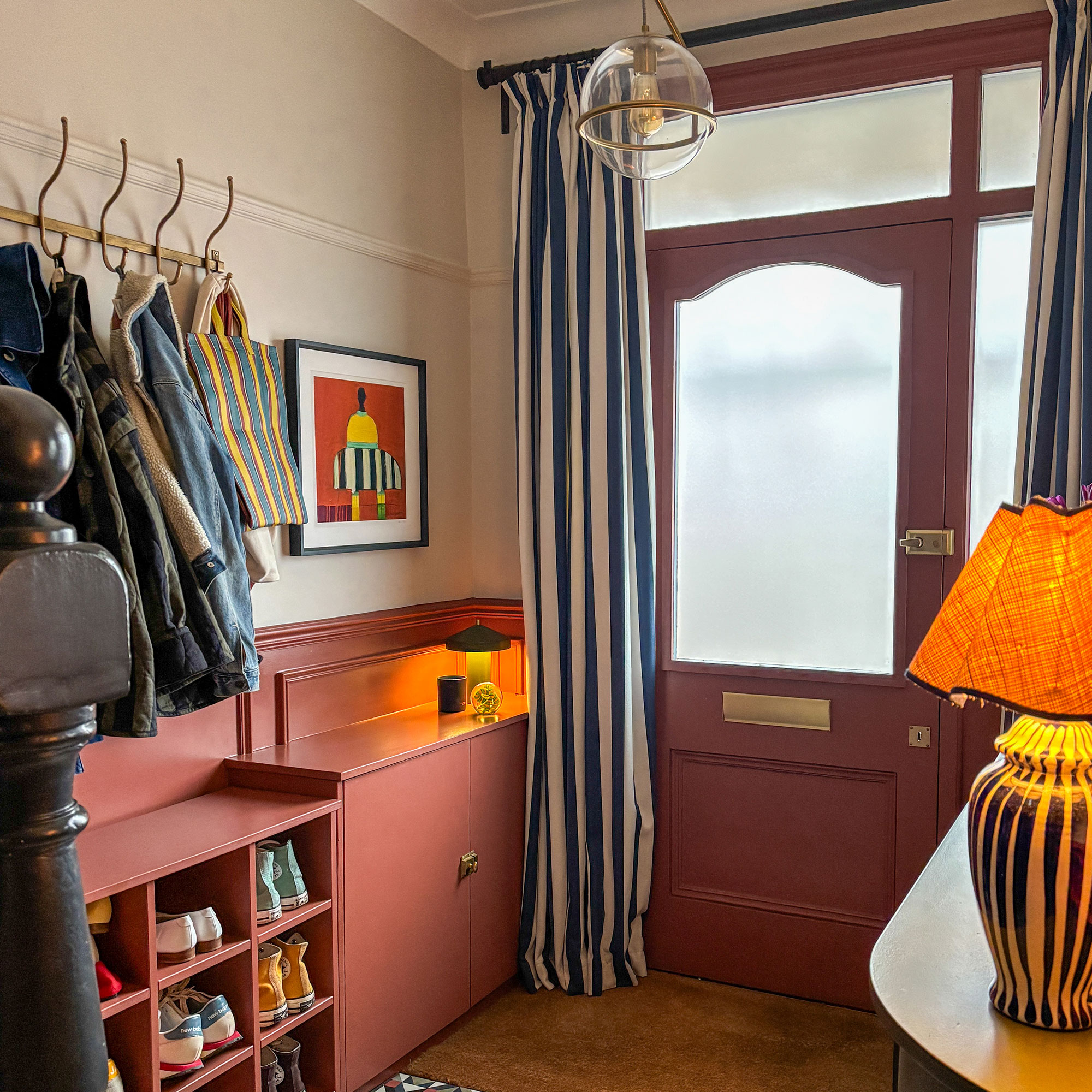Entrance of a home with terracotta and cream walls, striped door curtain and build in cupboard and shoe storage