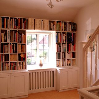 white stairway with book shelf and drawers