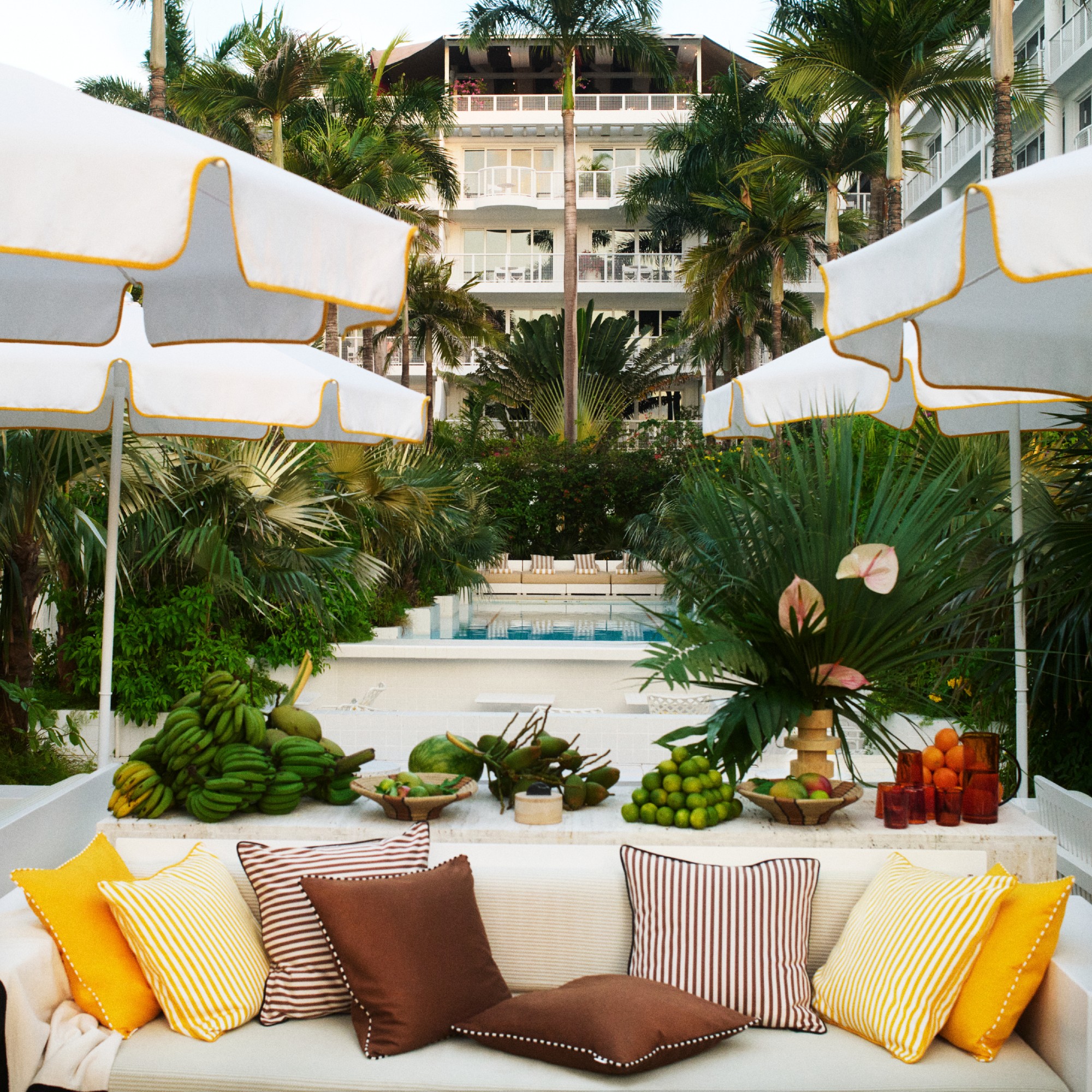 The outdoor space of the Palm Heights hotel with white yellow-trimmed parasols and bench covered in the H&M cushions from the collaboration