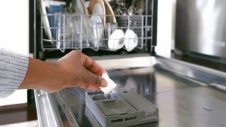 person placing a tablet inside a full dishwasher