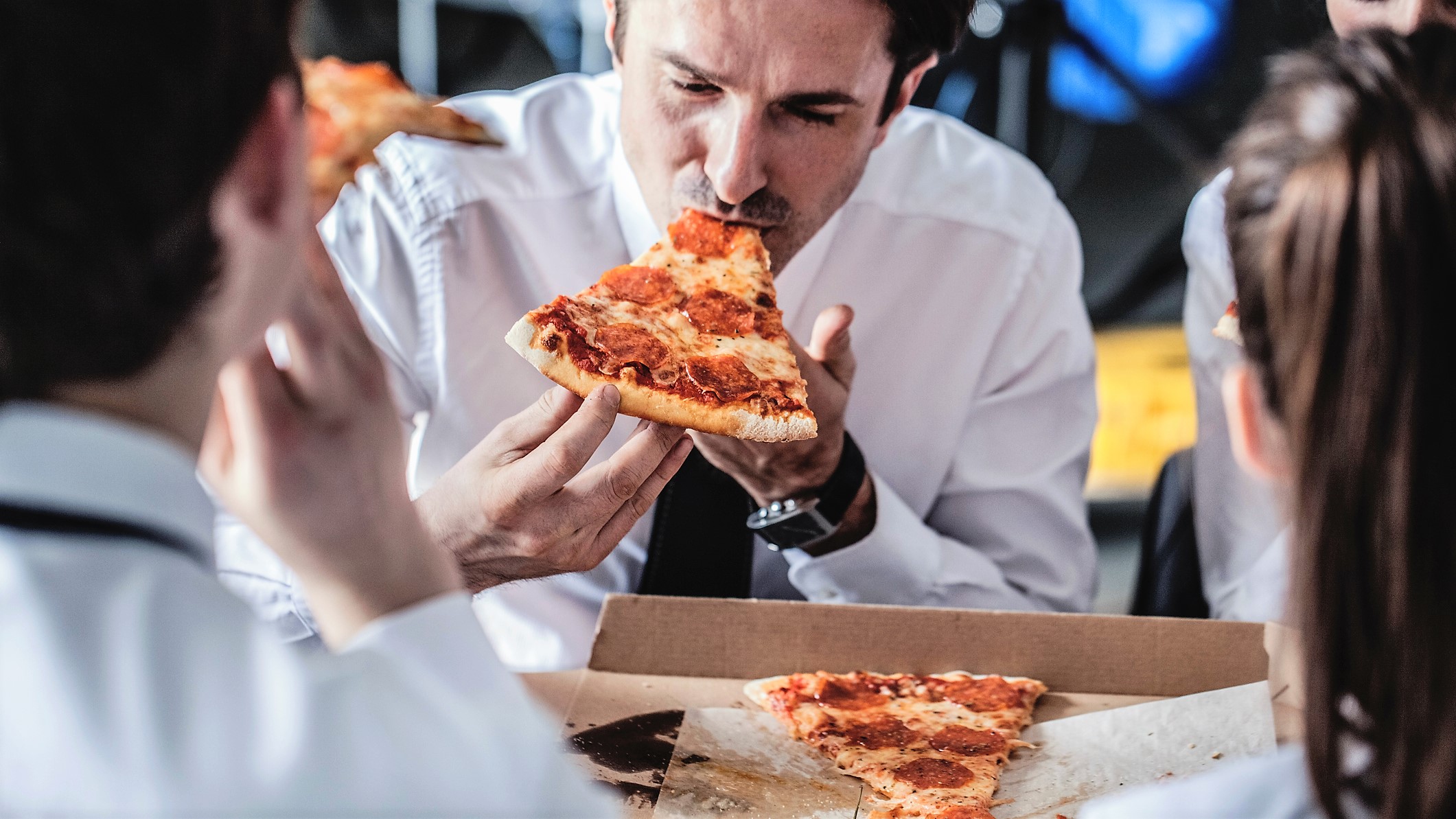 Business team in suits eat pizza together