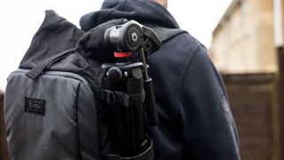 A photo of the tripod being carried on the side of a camera rucksack