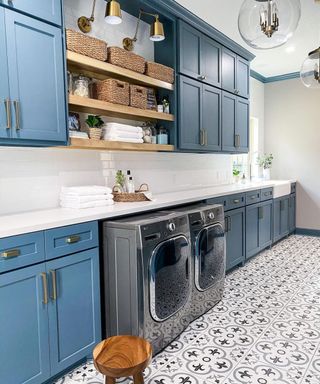 A blue laundry room with wooden shelves and brass lamp shade lighting