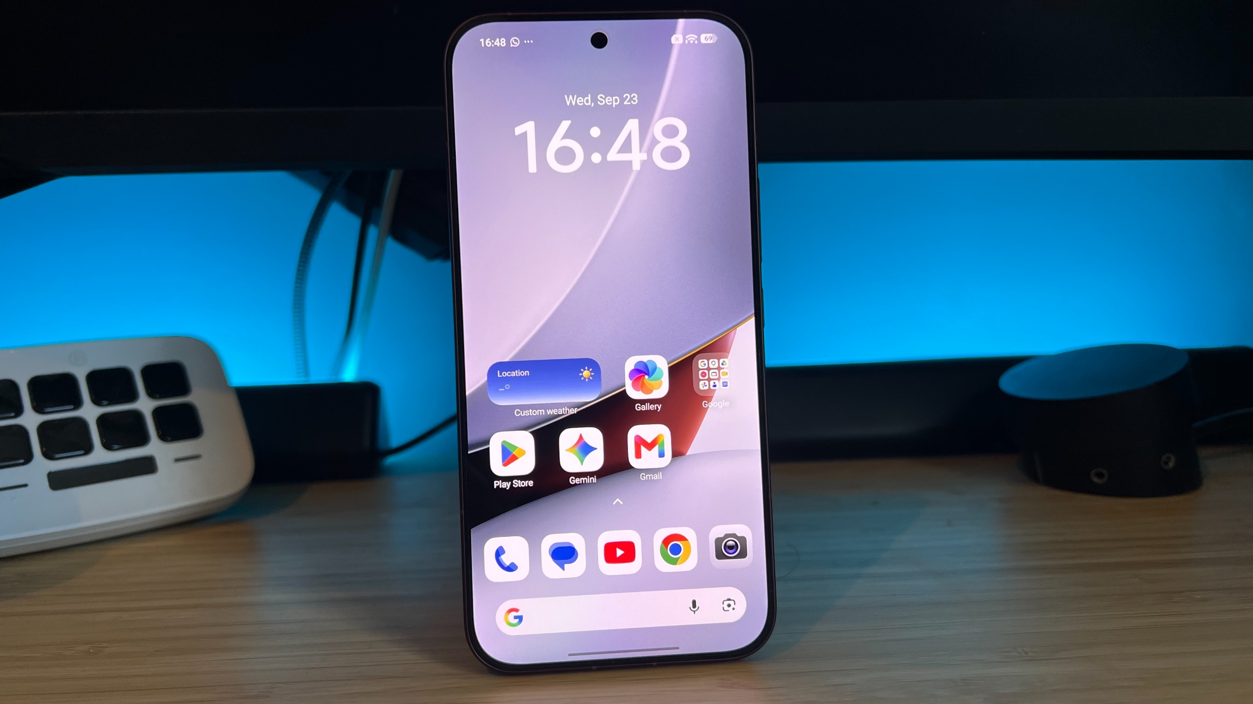 Poco F9 Ultra smartphone standing upright on a wooden desk display main homescreen page