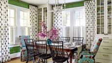 Dining room with green walls and patterned chairs and curtains 