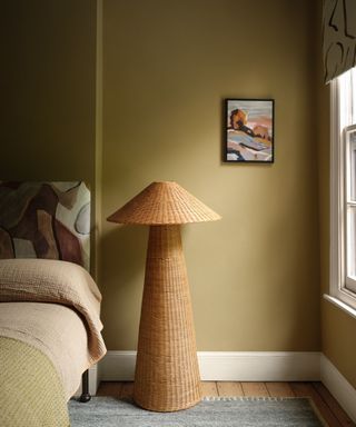 bedroom with dark yellow walls, woven bedside lamp, neutral bedding