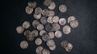 A pile of medieval silver coins on black velvet.